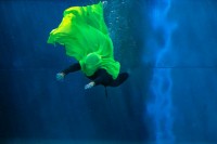 Grüner Farbklecks im blauen Wasser. Die Tänzer*innen spielen damit.